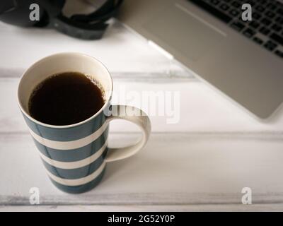 Bureau en bois avec ordinateur portable, écouteurs et grande tasse de cofee Banque D'Images