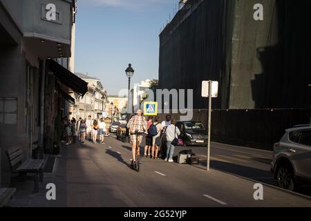 Moscou, Russie - 21 juin 2021, UNE fille de brune vêque d'un scooter électrique se déplace le long de la rue Bolshaya Nikitskaya le long d'une piste cyclable Banque D'Images