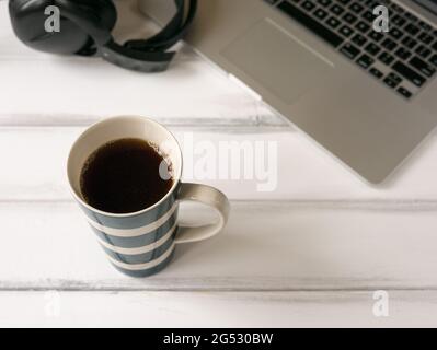 Bureau en bois blanc avec ordinateur portable et grande tasse de café Banque D'Images