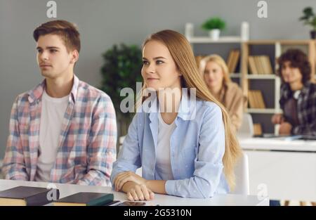 Étudiant adolescent assis à un bureau dans une salle de classe regardant et écoutant attentivement Banque D'Images