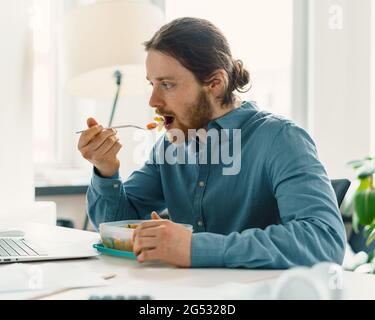 Homme affamé qui apprécie un repas végétalien pendant la pause déjeuner Banque D'Images