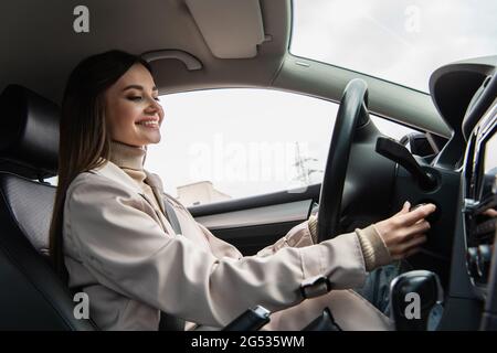 femme souriante en démarrant le moteur de la voiture Banque D'Images