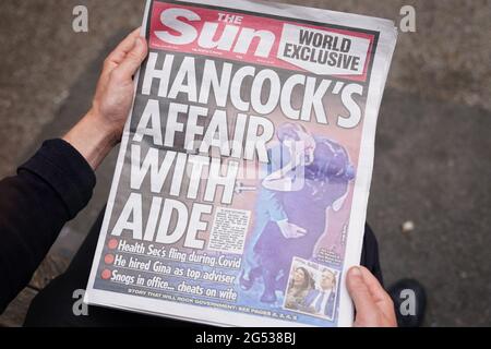 Une personne lit une copie du journal Sun à Westminster, Londres, avec l'histoire et les photos du secrétaire à la Santé Matt Hancock apparaissant pour embrasser son conseiller Gina Coladanangelo, que le journal a déclaré avoir été embauché par M. Hancock l'année dernière. Date de la photo: Vendredi 25 juin 2021. Banque D'Images