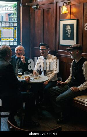 Trois hommes heureux buvant dans l'intérieur de pub, Angleterre, Londres, Tower Hamlets, Spitafield, le Golden Heart Pub Banque D'Images