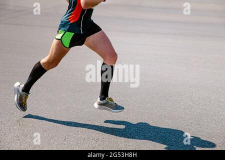 jambes coureur homme en chaussettes de compression noires course sur route Banque D'Images