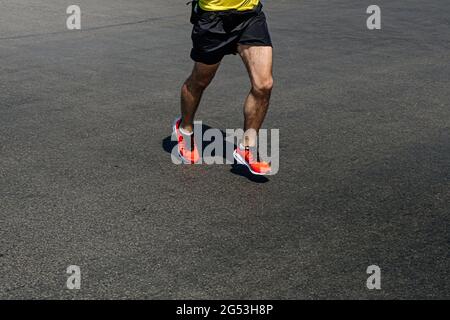 jambes coureur homme dans des chaussures orange courir sur la route sombre Banque D'Images