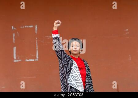 Italie, Toscane, Pistoia, femme debout contre le mur et levant le poing Banque D'Images