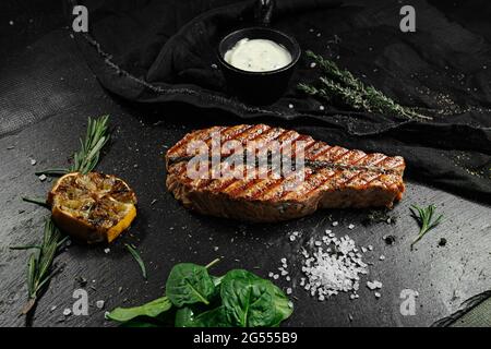 Un steak grillé aux herbes et au citron repose sur une pierre sombre Banque D'Images