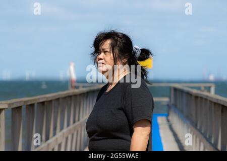 Une femme asiatique d'âge moyen sur une jetée avec un océan bleu et le ciel en arrière-plan. Photo du comté de Scania, Suède Banque D'Images