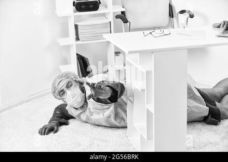 Malade sans défense. Fièvre et faiblesse. Maladie grave et décès. Homme est décédé. Essoufflement. Homme dans l'équipement de protection posé sur le sol. Grave Banque D'Images