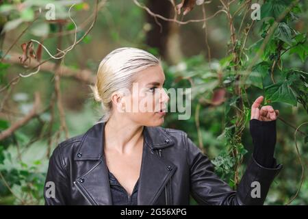 La mode dans des endroits insolites, jeune femme dans la veste de moto ébougée dans la forêt Banque D'Images