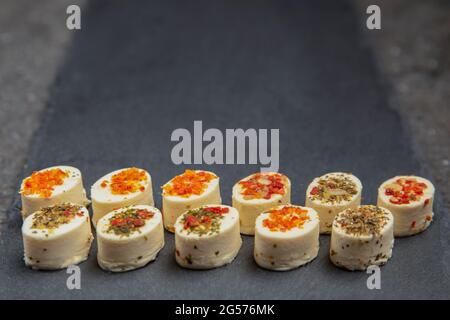 Plateau de fromages avec épices. Fromage Mazzarella aux différentes épices. En-cas au fromage de différentes saveurs sur fond de plateau en pierre noire ou bannière sur t Banque D'Images