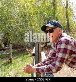 Un agriculteur senior s'est penché sur une clôture en bois près de Sun Valley Banque D'Images