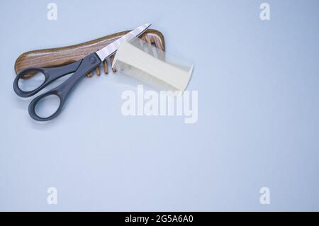 Vue de dessus des brosses à cheveux et des ciseaux sur fond bleu Banque D'Images