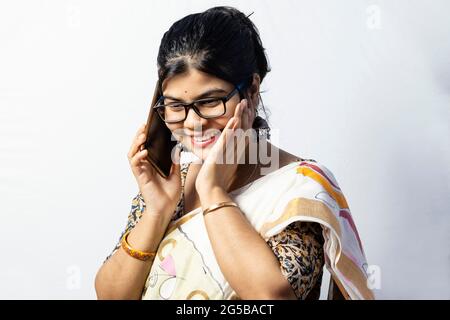 Une belle femme indienne en saree parlant sur un téléphone intelligent et souriant isolé sur fond blanc Banque D'Images