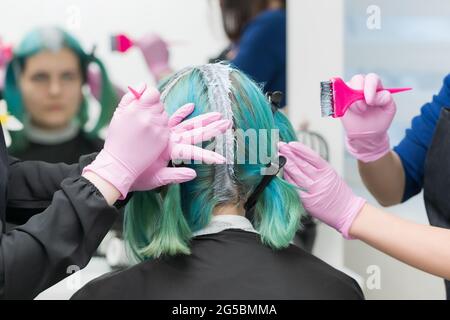 Deux maîtres coiffeurs professionnels appliquent de la peinture sur les cheveux de femme pendant le blanchiment des racines de cheveux. Processus de coloration des cheveux dans un salon de beauté professionnel. Banque D'Images