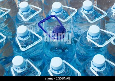 De nombreuses bouteilles en plastique bleu avec bouchons bleus et une avec bouchon bleu foncé avec eau minérale claire dans un supermarché. Eau pure, filtrée et écologique Banque D'Images