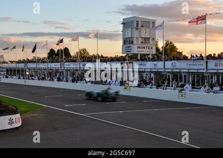 Course automobile historique en soirée avec une course automobile classique au Goodwood Revival 2012 en passant par la fosse au coucher du soleil. Une endurance recréante Banque D'Images