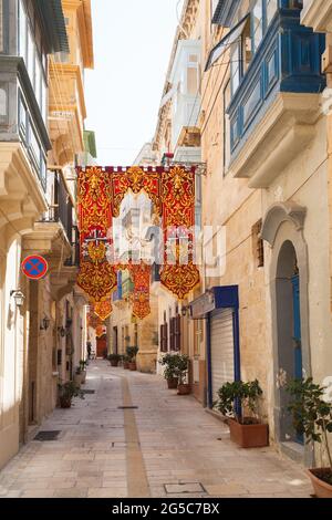 Vieille rue étroite, vue panoramique avec des drapeaux colorés, la Valette, Birgu, Malte Banque D'Images