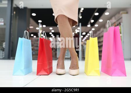 Sacs à provisions multicolores et jambes pour femmes dans des chaussures à l'entrée pour la fermeture du magasin Banque D'Images