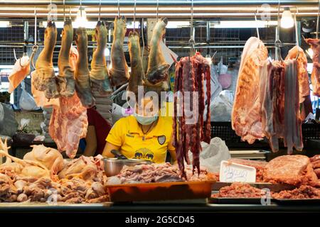 Bangkok, Thaïlande - 29 juin 2021 : boucherie de femme asiatique portant un masque de protection pour le covid ou le coronavirus padenomic et préparant le porc et le poulet. Banque D'Images