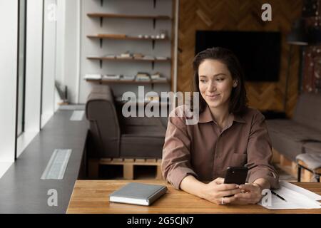 Jeune femme rêveuse assise à la table à la maison. Banque D'Images