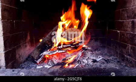Gros plan des flammes sur le feu de bois dans la cheminée avec de la fumée et des émbres incandescents. Banque D'Images