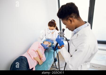 Équipe de médecins multiraciaux hommes et femmes effectuant la gastroscopie à l'hôpital, examinant l'estomac de la jeune patiente. Concept de la Fibrogastroduodénoscopie Banque D'Images