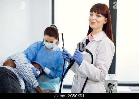 Concept d'endoscopie. Portrait d'une jeune femme caucasienne médecin tenant un endoscope avant l'endoscopie. Infirmière préparant le patient afro-américain masculin à la procédure Banque D'Images