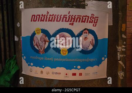 Au cours d'une épidémie de COVID - 19, l'USAID présente des affiches dans un script khmer avertissant les gens de se laver les mains, d'utiliser un désinfectant pour les mains et de porter des masques, dans un bidonville près du marché de Kandal, pendant la pandémie du coronavirus. Phnom Penh, Cambodge. 22 février 2021. © Kraig Lieb Banque D'Images