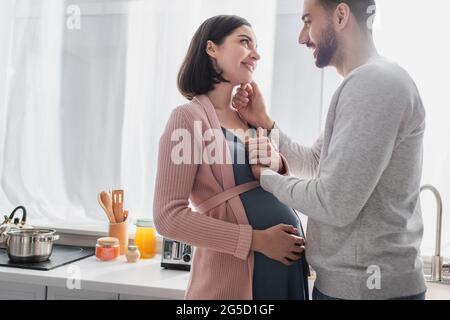 jeune homme heureux touchant le visage de la femme enceinte dans la cuisine Banque D'Images