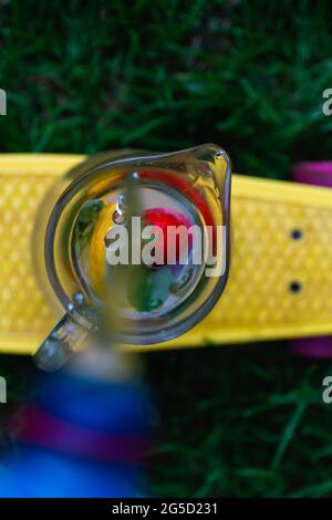 Des gouttes de flou artistique et un jet d'eau versé dans une bouteille en plastique dans une carafe en verre de limonade à la fraise, trancher le citron et les feuilles de menthe sur un penny jaune Banque D'Images