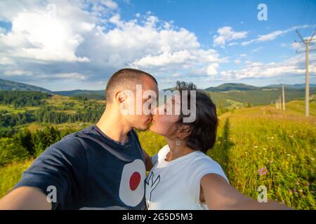 Un jeune couple prend son selfie avec un paysage de montagne incroyable. Banque D'Images