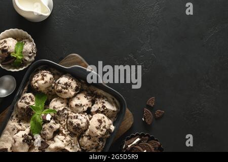 Crème glacée crémeuse sans sucre de fraîcheur avec biscuits dans un récipient sur fond noir avec espace de copie. Vue de dessus. Délicieux dessert pour les enfants sans Banque D'Images