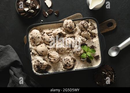 Crème glacée crémeuse et fraîche avec biscuits dans un récipient sur fond noir. Vue de dessus. Dessert sans sucre pour manger propre. Banque D'Images
