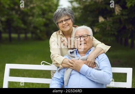 Portrait d'un couple d'amour actif et souriant sur banc dans le parc Banque D'Images