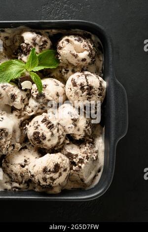 Crème glacée maison crémeuse aux biscuits dans un récipient sur fond noir. Vue de dessus. Dessert savoureux et propre, sans sucre. Orientation verticale Banque D'Images