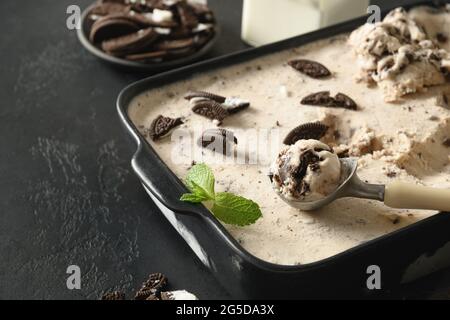 Crème glacée maison crémeuse avec biscuits au café dans un récipient sur fond noir avec espace de copie. Gros plan. Dessert savoureux pour enfants sans sucre. Banque D'Images