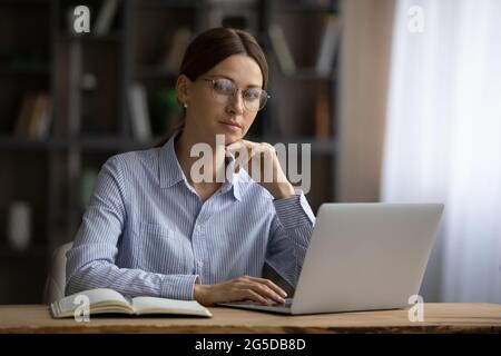 Portrait d'une femme d'affaires heureuse des années 30 en lunettes posant au bureau. Banque D'Images