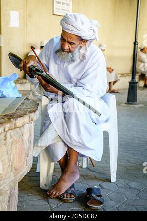 Nizwa, Oman, 2 décembre 2016 : un homme âgé inspecte une carabine de chasse au marché des armes du vendredi à Nizwa, en Omam Banque D'Images