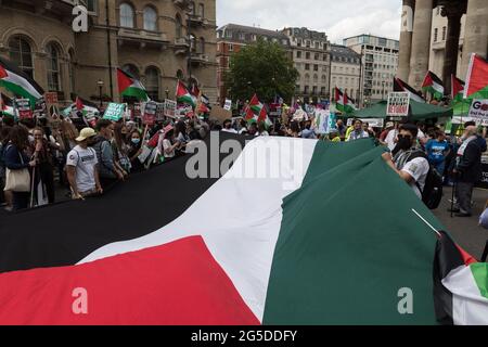 Londres, Royaume-Uni. 26 juin 2021. Les manifestants arborent un drapeau palestinien alors que le théyt se réunissait devant la BBC Broadcasting House avant l'Assemblée du peuple contre la manifestation nationale d'austérité et la marche dans le centre de Londres. Des manifestants de diverses organisations protestent contre la gestion par le Gouvernement de la pandémie du coronavirus et exigent la renationalisation des industries clés, la lutte contre le racisme institutionnel et l'action contre l'urgence climatique. Crédit: Wiktor Szymanowicz/Alamy Live News Banque D'Images