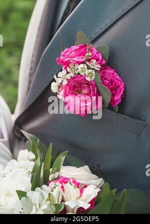 Boutonnière rose sur le costume gris du marié, gros plan, élément de mariage de la décoration de l'homme. Banque D'Images