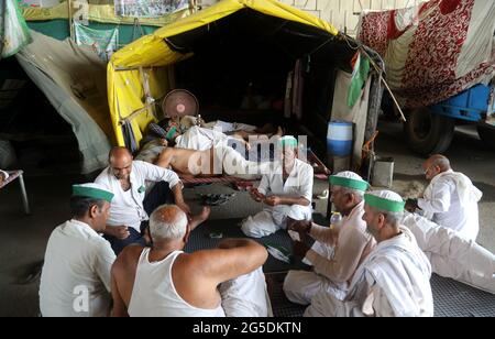 New Delhi, Inde. 26 juin 2021. Les agriculteurs jouant des cartes dans un groupe pendant les agriculteurs protestent contre trois lois de réforme agricole à la frontière de Ghazipur.les agriculteurs assis sur les frontières de Delhi depuis sept mois sous la direction du syndicat des agriculteurs Samyukt Kisan Morcha. Les agriculteurs observent le 26 juin sous le nom de Kheti Bachao, Loktantra Bachao Diwas (Save Agriculture, Save Democracy Day). Les agriculteurs exigent également de définir légalement le MSP (prix de soutien minimum). Crédit : SOPA Images Limited/Alamy Live News Banque D'Images
