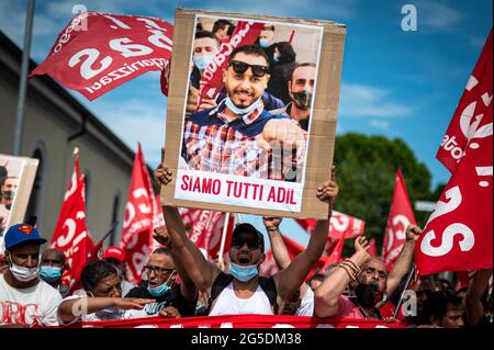 Novara, Italie. 26 juin 2021. Un démonstrateur tient un écriteau intitulé « We are all Adil » lors d'une manifestation organisée par le syndicat si Cobas pour protester contre le meurtre d'Adil Belakhdim. Le syndicaliste Adil Belakhdim est décédé vendredi 18 juin après avoir été frappé par un camion qui a forcé le blocus organisé par les travailleurs lors d'une grève devant l'entrepôt de Lidl à Biandrate, près de Novara. Credit: Nicolò Campo/Alay Live News Banque D'Images