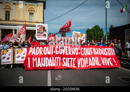 Novara, Italie. 26 juin 2021. Les manifestants tiennent une bannière lisant 'maîtres, gouvernement, Confindustria, vous êtes les instigateurs! Adil vit !' Lors d'une manifestation organisée par le syndicat si Cobas pour protester contre l'assassinat d'Adil Belakhdim. Le syndicaliste Adil Belakhdim est décédé vendredi 18 juin après avoir été frappé par un camion qui a forcé le blocus organisé par les travailleurs lors d'une grève devant l'entrepôt de Lidl à Biandrate, près de Novara. Credit: Nicolò Campo/Alay Live News Banque D'Images