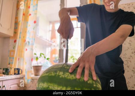 Cropped shot de pastèque coupe personne dans la cuisine à la maison Banque D'Images