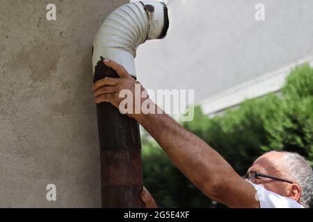 Homme installant une vieille stovepipe d'étain extérieur pour un poêle à bois à la maison. Gros plan et espace de copie Banque D'Images