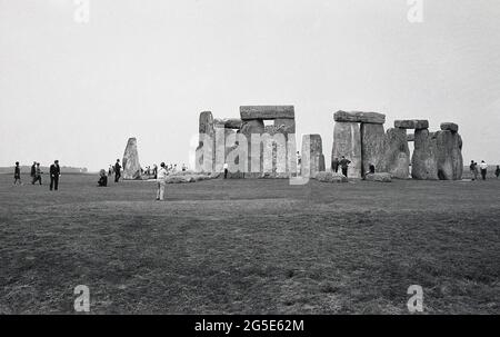 Années 1960, vue historique et extérieure des visiteurs des anciennes pierres de Stonehenge, Wiltshire, Angleterre, Royaume-Uni. Dans cette époque et dans les époques précédentes, on pouvait marcher librement autour des pierres préhistoriques mais dans la décennie suivante, en 1977, en raison du nombre croissant de visiteurs et des dommages à l'herbe et l'érosion générale au site sacré, ancien enterrement, les pierres ont été torties pour empêcher l'accès. Situé sur le domaine de l'abbaye d'Amesbury, propriété à une époque du roi Henri VIII, Cecil Chubb a apporté la parcelle de terre avec les pierres lors d'une vente aux enchères en 1915 et en 1918 l'a donné à la nation britannique. Banque D'Images