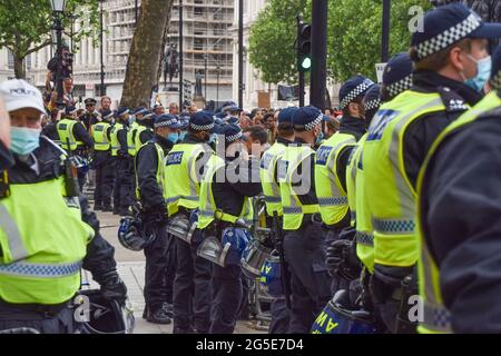 Londres, Royaume-Uni. 26 juin 2021. La police anti-émeute observe les manifestants à l'extérieur de Downing Street pendant la manifestation. Des manifestants anti-verrouillage et anti-vaccination se sont de nouveau rassemblés dans le centre de Londres pour protester contre d'autres blocages, masques et passeports de vaccination. Crédit : SOPA Images Limited/Alamy Live News Banque D'Images