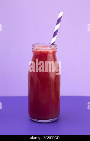 Smoothie aux baies dans une carafe en verre avec une paille Banque D'Images